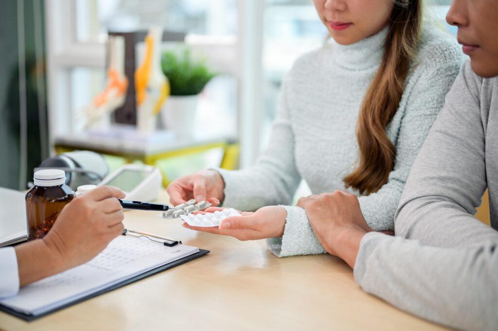 A close-up of a doctor explaining the instructions for the medication to a patient during the visit in an examination room. health care concept